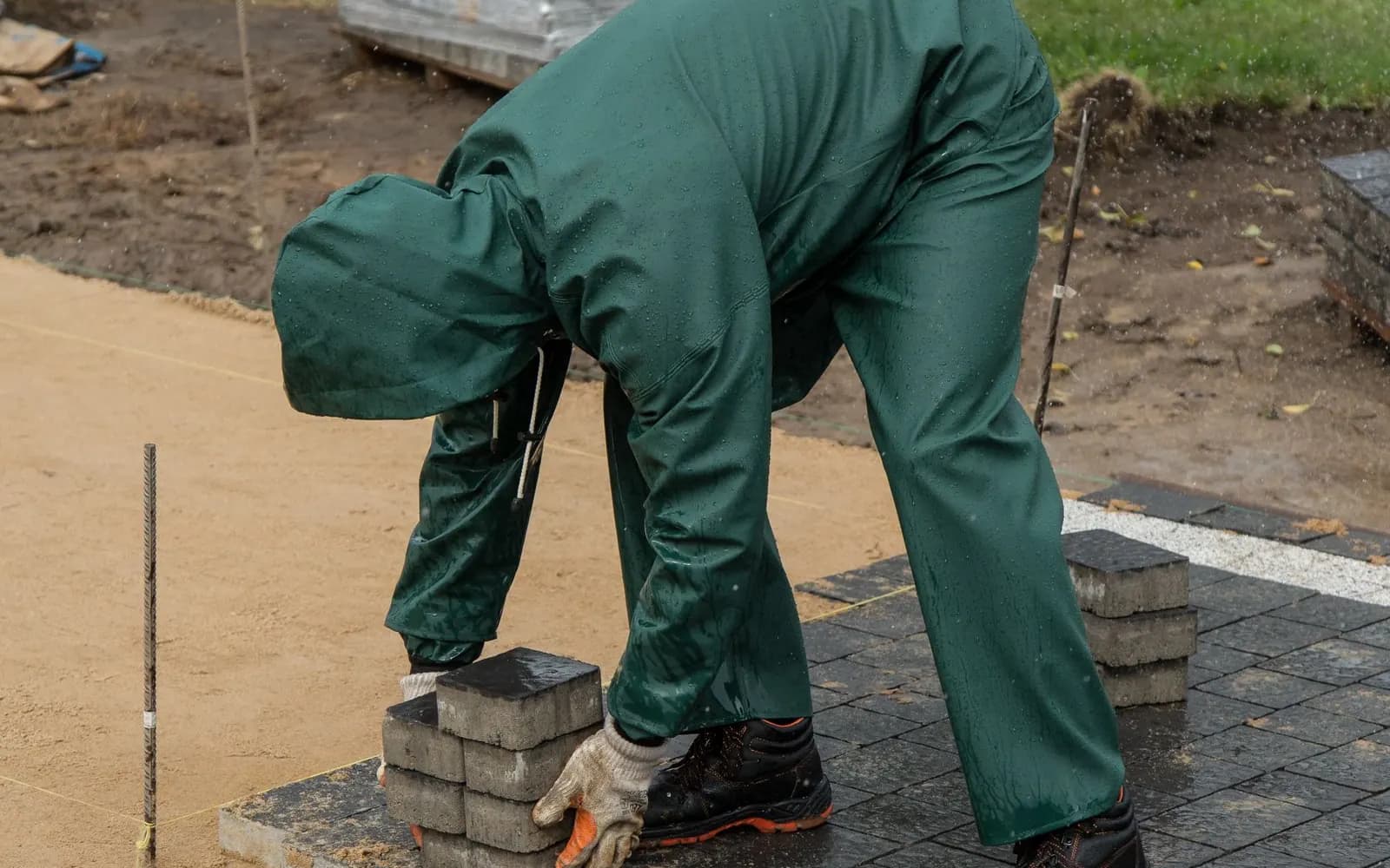 Worker laying interlock paving blocks on a prepared sub-base